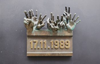 Národní třída, targa commemorativa opera degli artisti Miroslav Krátký e Otakar Příhoda. Le due dita alzate al cielo con il segno di vittoria sono uno dei simboli della Rivoluzione di Velluto.