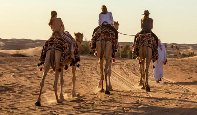 A dorso di cammello nel deserto verso la città del futuro